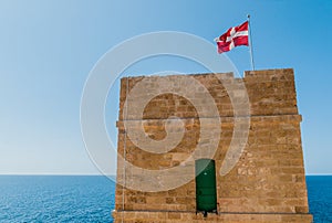 Old tower with red flag in Malta