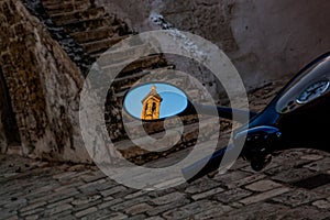 The old town of Bari Italy. The reflection of a church tower in the rear view mirror of a scooter automobile