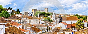 Old town skyline of Obidos, Portugal with house roof tops, church towers and the wall of the medieval castle located in the civil