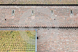 Old town-wall of bricks and two roofs with tiles