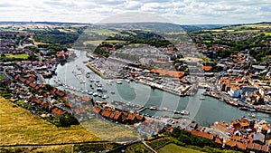 Old town Whitby from the sky, boats on the river, sunny cloudy day