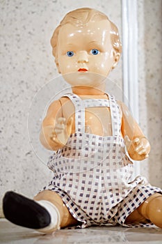 An old toy is a vintage doll with blue eyes, dressed in a jumpsuit. Subject from the past