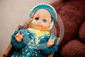 Old toy is a vintage doll with blue eyes in a woolen hat. Item from the past