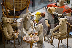 Old toys teddy bears are sitting at the table in a mini museum