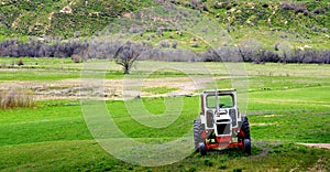 Old Tractor on Farm Field Green with Hills Mountains