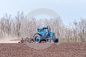 An old tractor in the field plows the land. Spring landscape of a countryside, a farm