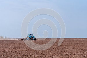 An old tractor in the field plows the land. Spring landscape of a countryside, a farm