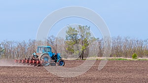 An old tractor in the field plows the land. Spring landscape of a countryside, a farm