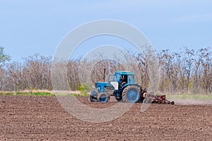 An old tractor in the field plows the land. Spring landscape of a countryside, a farm
