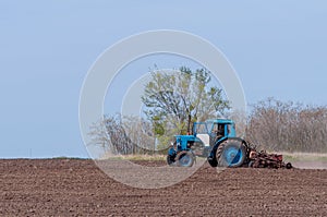 An old tractor in the field plows the land. Spring landscape of a countryside, a farm