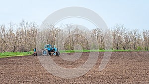 An old tractor in the field plows the land. Spring landscape of a countryside, a farm