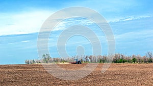 An old tractor in the field plows the land. Spring landscape of a countryside, a farm