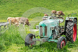 Old tractor on meadow. Beautiful mountain view in the Alps