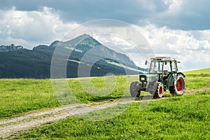 Old tractor on meadow. Beautiful mountain view in the Alps