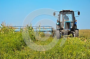 Old tractor mowing corn in the field closeup