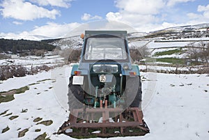 Old tractor parked in the middle of a snowy meadow