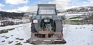 Old tractor parked in the middle of a snowy meadow