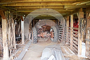 Old tractor parked in a rustic wooden barn