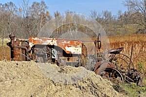 Old tractor partially hidden behind a pile of clay soil.