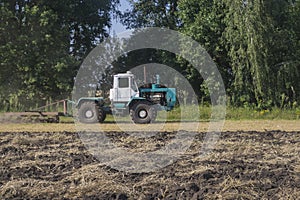 old tractor ploughs a field after harvesting of the grain