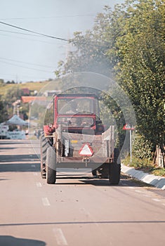 Old tractor on the streets of a village in rural Romania with plenty of vegetation around