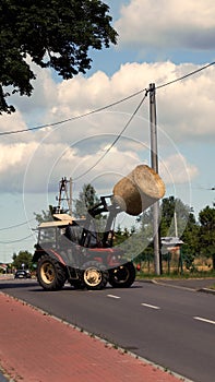 An old tractor transporting a bale of hay