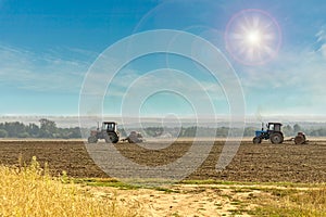 Old tractors with seeders on beautiful sunny agricultural landscape.