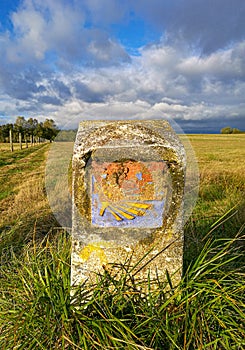 Old traditional camino yellow shell symbol on milestone