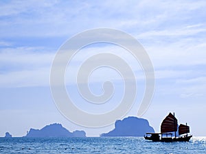 Old traditional chinese boat cruising the sea in south Thailand around rock formations in the sea, Krabi, Thailand