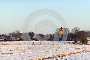 Old traditional church and fields in snow in Hippolytushoef at winter, North Holland, Netherlands