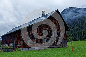 Old traditional country farmhouse in alpine region, misty scenery