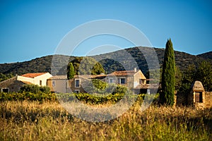 Old traditional stone provencale farmyard in Provence, France with Luberon hill on background in hot summer morning with clear