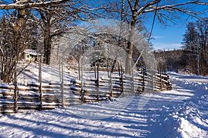 Old traditional Swedish wooden fence in winter sunny day.