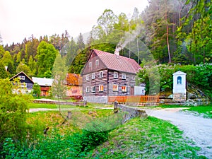 Old traditional timbered cottage with romantic with stone bridge at evening time. Czech rural architecture