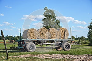 Old trailer with bales of straw standing in a meadow