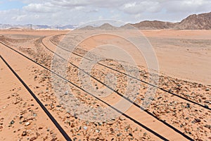 Old train rails almost completely covered with desert sand in Wadi Rum, Jordan