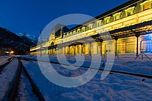 Old train station of Canfranc with the facade illuminated on a winter night with snow on the tracks, Huesca, Spain