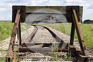 Old train tracks with a wooden stop device. Composition with leading lines.