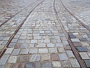 Old tram rails on paving stones converging towards the horizon, selective focus
