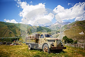 Old truck in a mountainous area against the mountain top of Kazbek in Georgia.