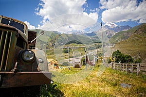 Old truck in a mountainous area against the mountain top of Kazbek in Georgia.