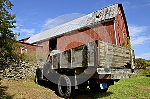 Old truck parked in front of a large barn