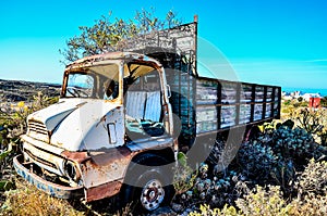 An old truck is sitting in a field with a blue sky in the background