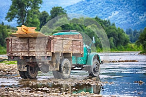 Old truck transports cargo wade across the river.