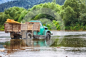 Old truck transports cargo wade across the river