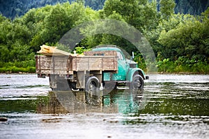 Old truck transports cargo wade across the river