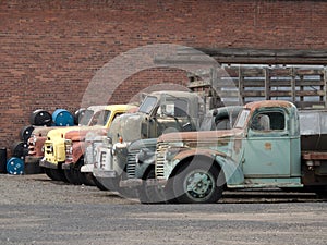 Old trucks parked against a brick wall backdrop