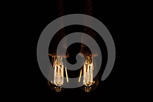 Old tungsten light bulb with their golden glow suspended with thick rope hangers