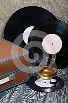 Old turntable. Nearby is a glass of strong alcohol and an empty glass bottle. Retro party equipment