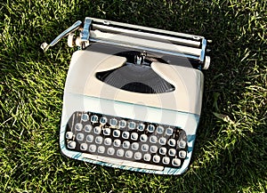 Old turquoise typewriter on the grass